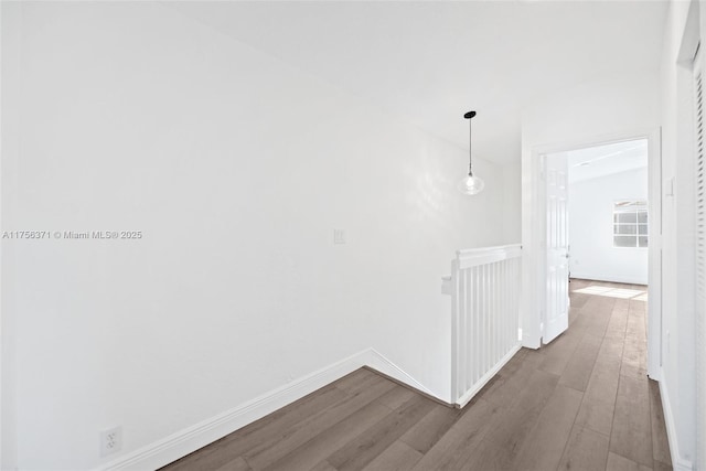 hall with baseboards, wood finished floors, and an upstairs landing
