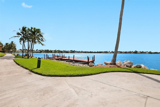 view of dock with a lawn and a water view