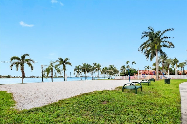 view of home's community featuring volleyball court, a lawn, a water view, and fence