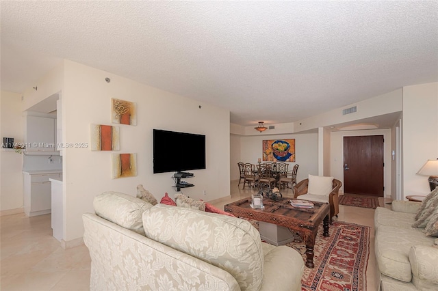 living room with a textured ceiling, light tile patterned floors, and visible vents