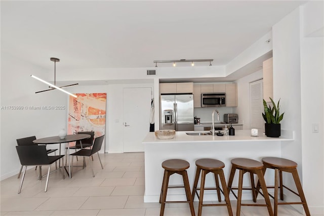 kitchen featuring stainless steel appliances, visible vents, a sink, a peninsula, and a kitchen breakfast bar