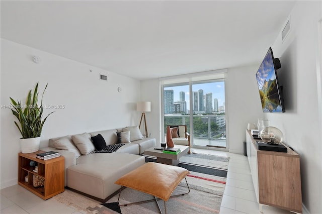 living room with baseboards, light tile patterned flooring, visible vents, and floor to ceiling windows