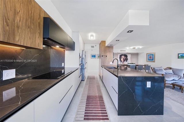 kitchen featuring range hood, open floor plan, a sink, and modern cabinets