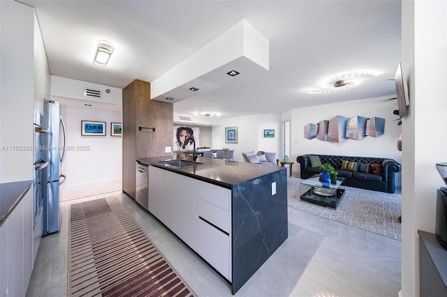 kitchen featuring stainless steel appliances, open floor plan, white cabinets, a sink, and modern cabinets