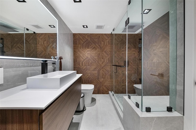 full bath with visible vents, a stall shower, toilet, and tile walls