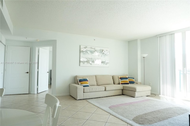 living room featuring light tile patterned flooring, a textured ceiling, and baseboards