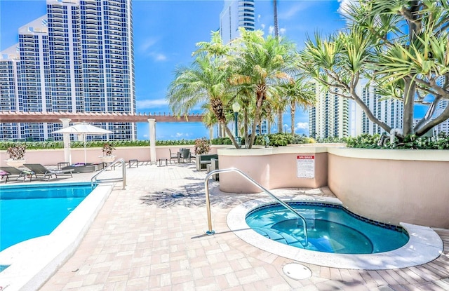 community pool featuring a hot tub, a city view, and a patio