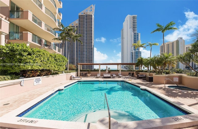 community pool with a patio area, a city view, and a pergola