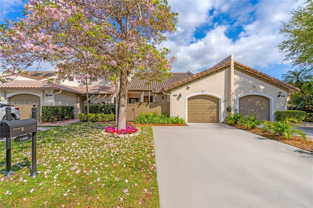 mediterranean / spanish house with a tile roof, concrete driveway, a garage, and stucco siding