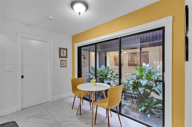 dining room with marble finish floor, a textured ceiling, and baseboards