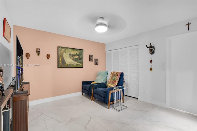 sitting room featuring baseboards, marble finish floor, and ceiling fan