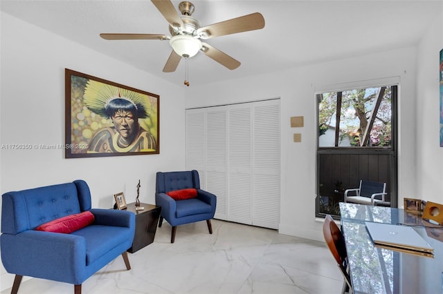 sitting room with baseboards, marble finish floor, and ceiling fan