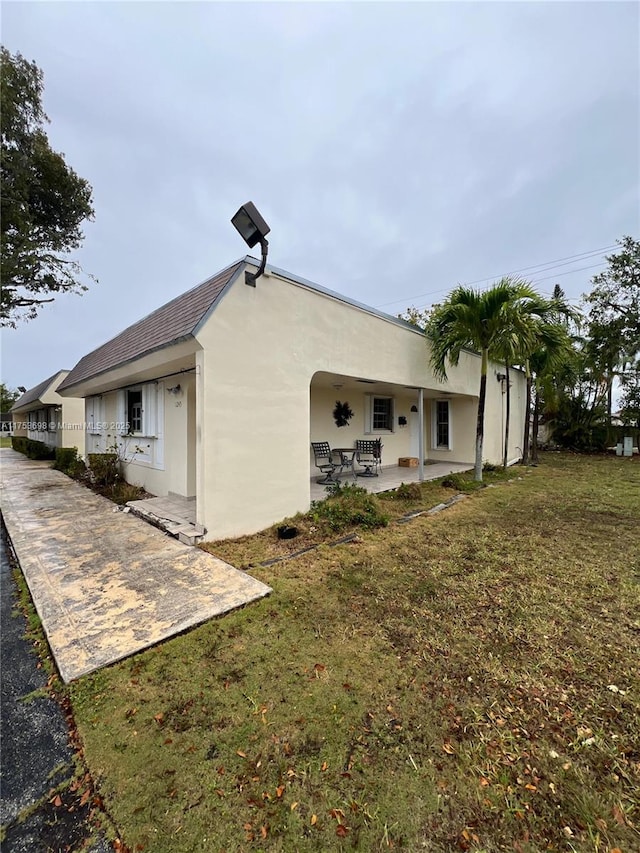 back of house featuring a patio area, a lawn, and stucco siding