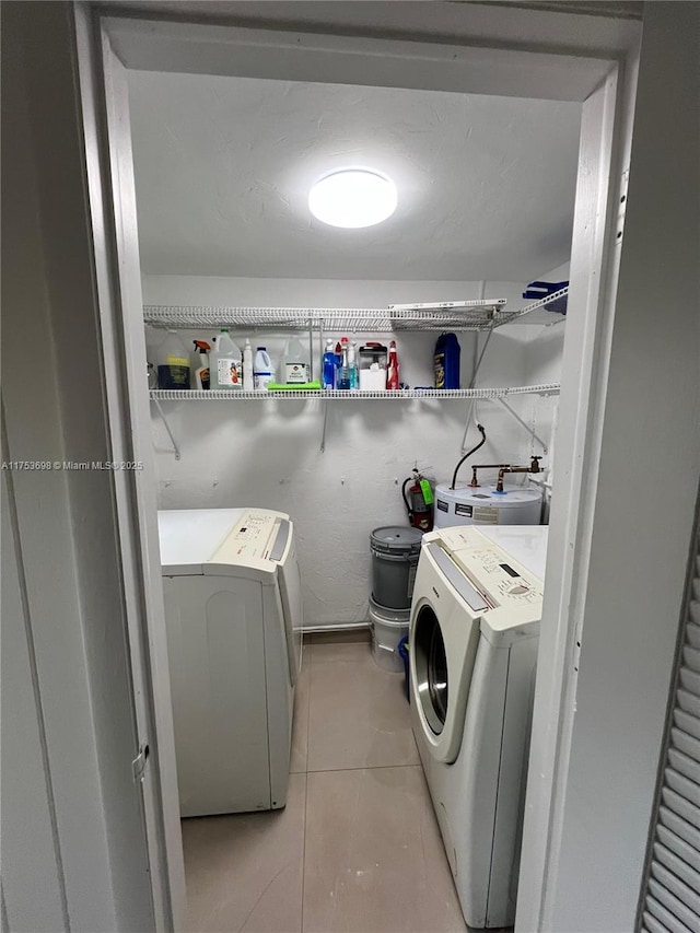 laundry room featuring light tile patterned floors, laundry area, water heater, and washing machine and clothes dryer