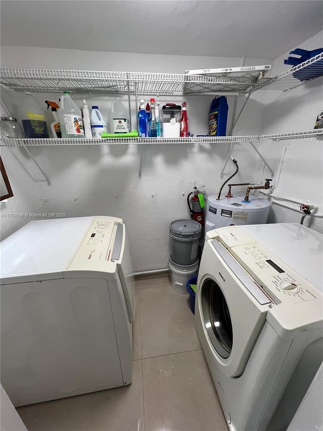 clothes washing area with washing machine and dryer, laundry area, water heater, and light tile patterned floors