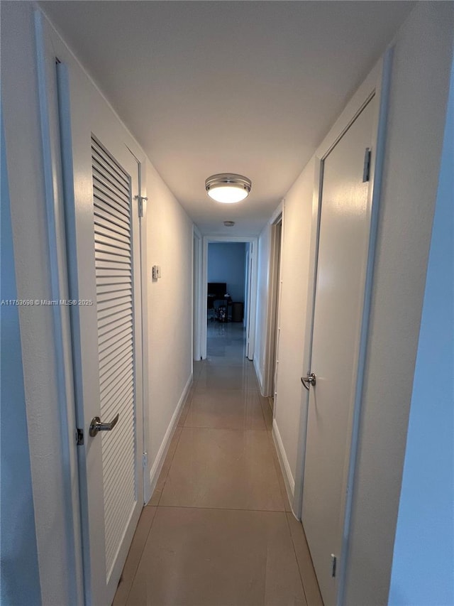 hall featuring light tile patterned floors and baseboards