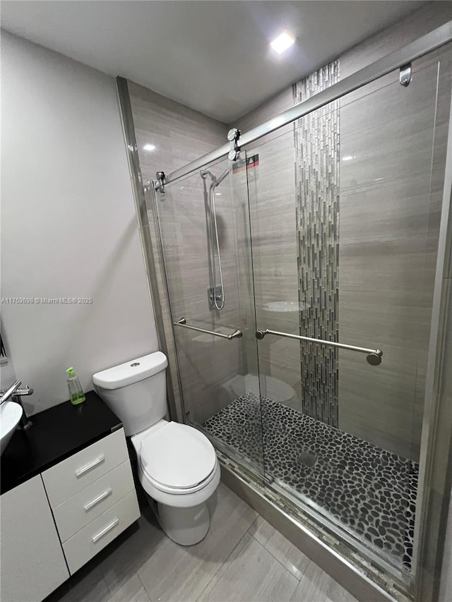 bathroom with a shower stall, toilet, and vanity