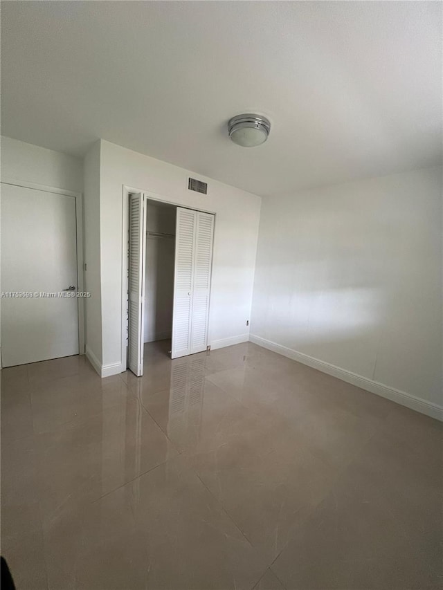 unfurnished bedroom with a closet, visible vents, and baseboards