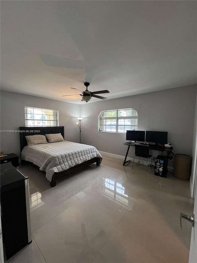 bedroom with ceiling fan, multiple windows, tile patterned flooring, and baseboards