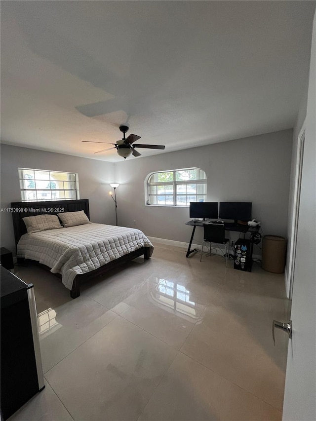 tiled bedroom with ceiling fan and baseboards