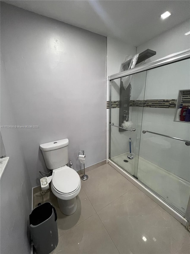 full bathroom with tile patterned flooring, baseboards, a shower stall, and toilet