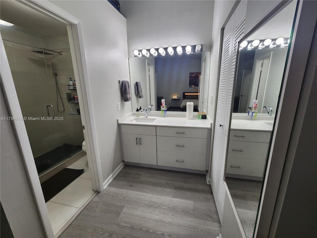 full bathroom with toilet, wood finished floors, vanity, baseboards, and a stall shower