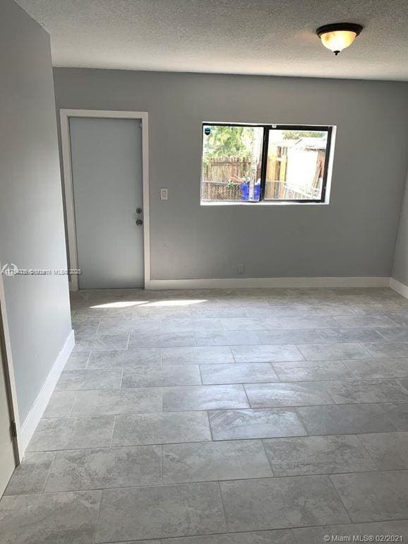 empty room with a textured ceiling and baseboards