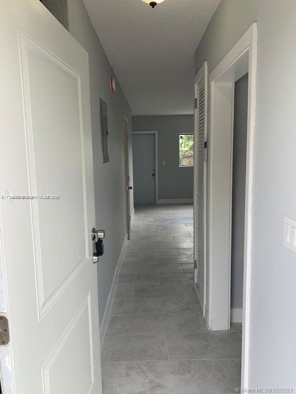 hallway featuring baseboards and a textured ceiling