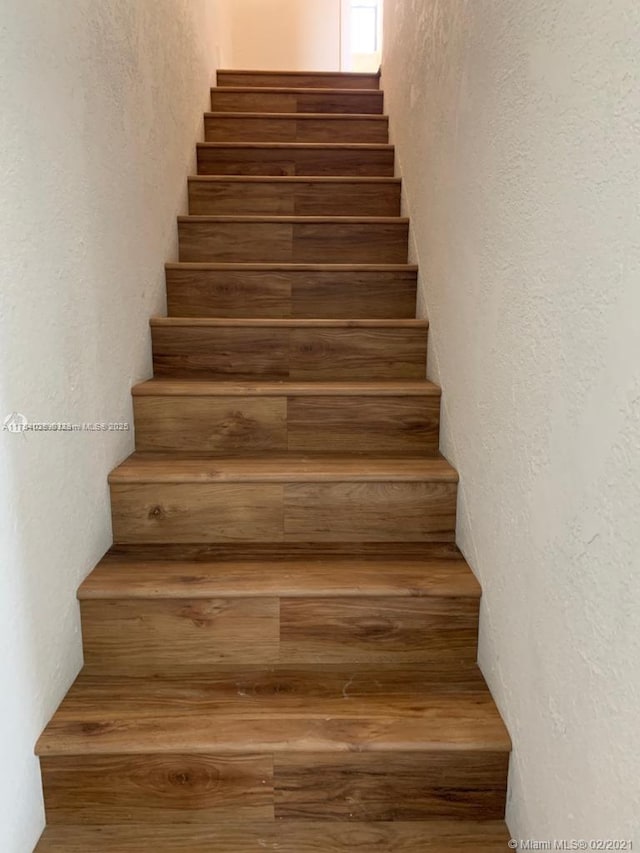 staircase with a textured wall and wood finished floors