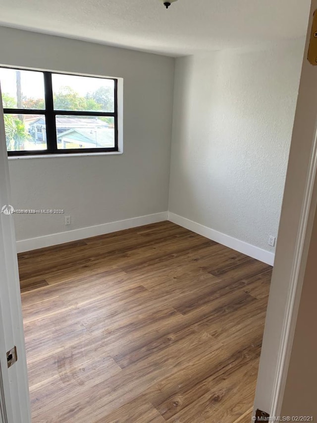 spare room with wood finished floors and baseboards