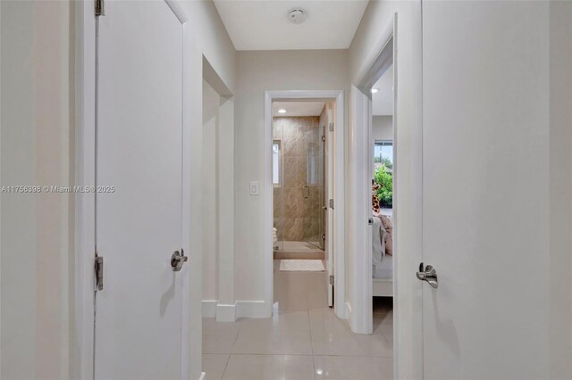 hallway featuring light tile patterned floors and baseboards