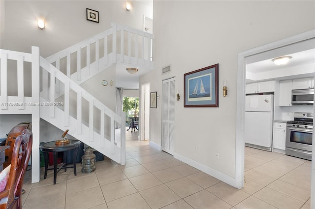 foyer entrance featuring light tile patterned floors, stairway, visible vents, and baseboards