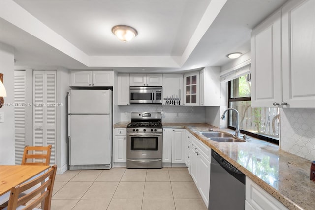 kitchen featuring appliances with stainless steel finishes, a raised ceiling, a sink, and light tile patterned flooring