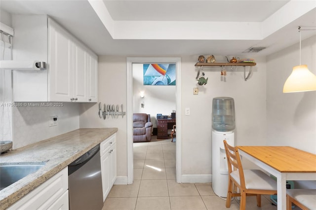 kitchen featuring a raised ceiling, white cabinets, stainless steel dishwasher, and light tile patterned floors