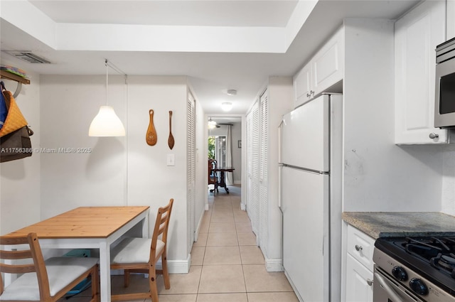 kitchen with light tile patterned floors, stainless steel appliances, visible vents, baseboards, and white cabinetry