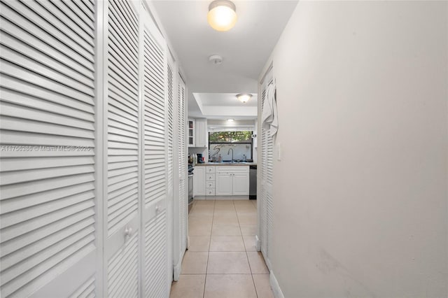 hallway with light tile patterned floors and a sink