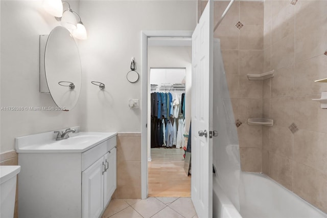 full bathroom with a wainscoted wall, tile walls, shower / bath combo with shower curtain, vanity, and tile patterned flooring