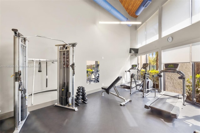 gym featuring a high ceiling and baseboards