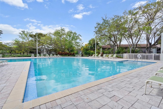 pool with a patio area and fence