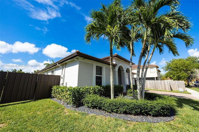 view of side of home featuring a yard, fence, and stucco siding