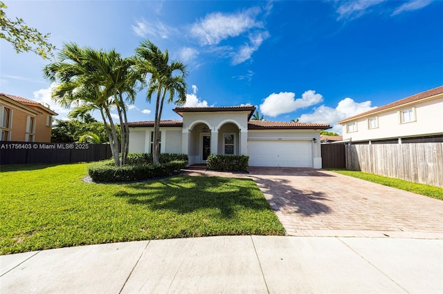 mediterranean / spanish-style home with a garage, decorative driveway, a front yard, and fence