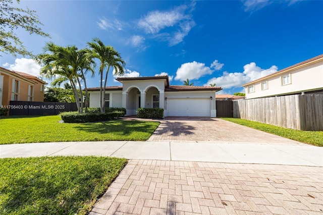 mediterranean / spanish house with stucco siding, an attached garage, fence, decorative driveway, and a front yard