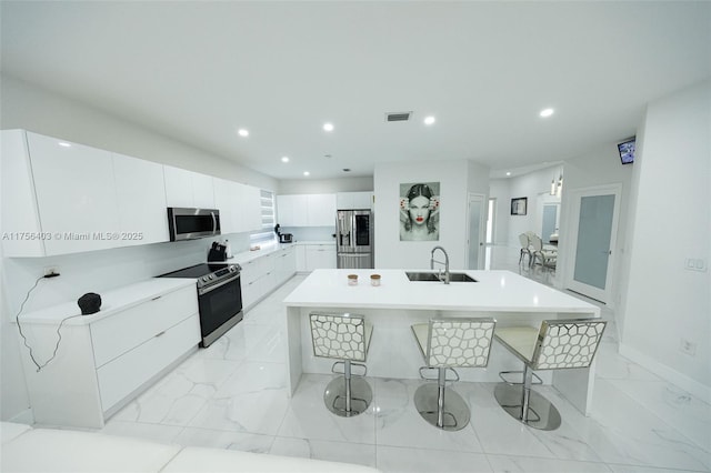 kitchen featuring visible vents, an island with sink, marble finish floor, stainless steel appliances, and a sink