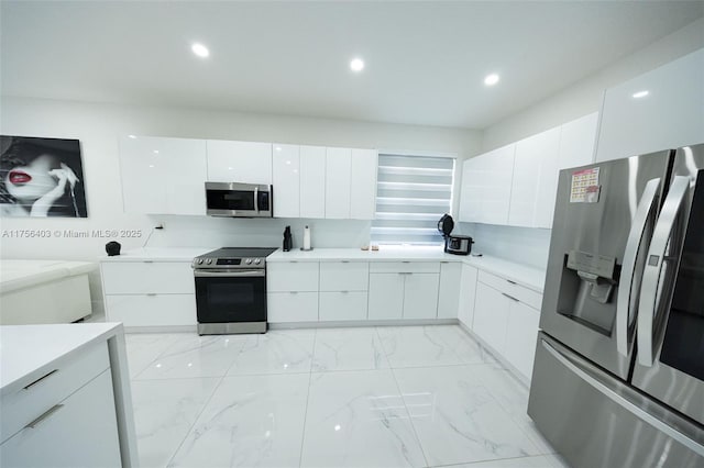 kitchen featuring marble finish floor, light countertops, appliances with stainless steel finishes, white cabinetry, and modern cabinets