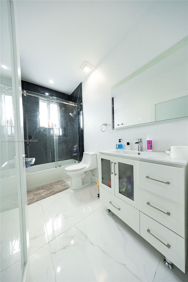 bathroom featuring toilet, visible vents, vanity, marble finish floor, and combined bath / shower with glass door