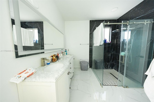 full bath featuring double vanity, marble finish floor, a shower stall, and a sink