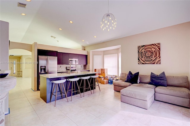 living room featuring visible vents, arched walkways, light tile patterned flooring, a notable chandelier, and recessed lighting