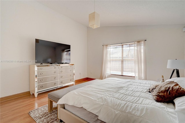 bedroom featuring baseboards, vaulted ceiling, and light wood finished floors