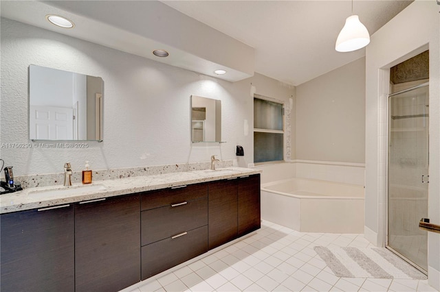 bathroom featuring double vanity, a stall shower, a garden tub, and a sink