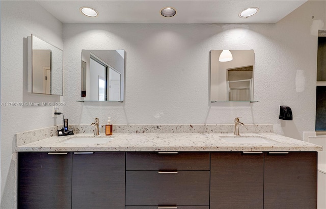 full bathroom with double vanity, a sink, and a textured wall